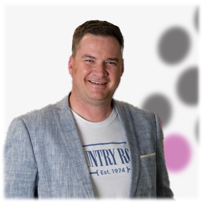 A man smiling in front of a polka dot background.